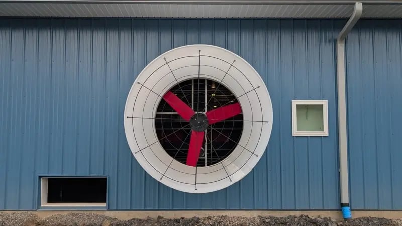 Large ventilation fan on the outer wall of a blue building