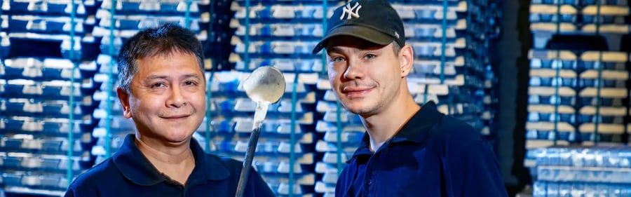 Twee werknemers werkzaam in zwaartekrachtgieten met metalen mallen voor een stapel metaal