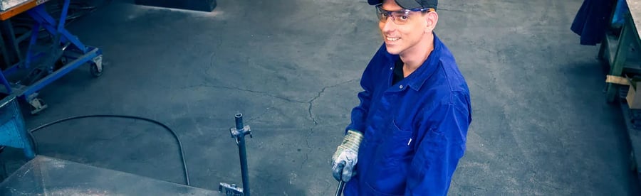 Werknemer glimlacht tijdens het werken aan zwaartekrachtgieten in een ruime werkplaats