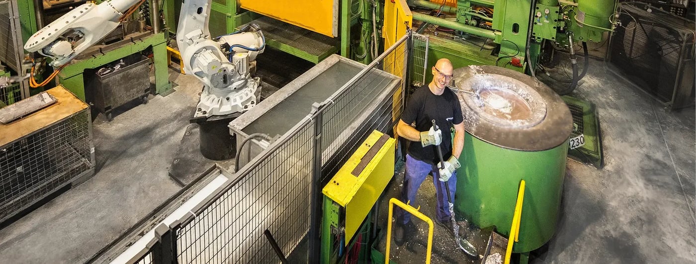 Werknemer met beschermende handschoenen bedient machines in een gietfabriek naast gesmolten metaal