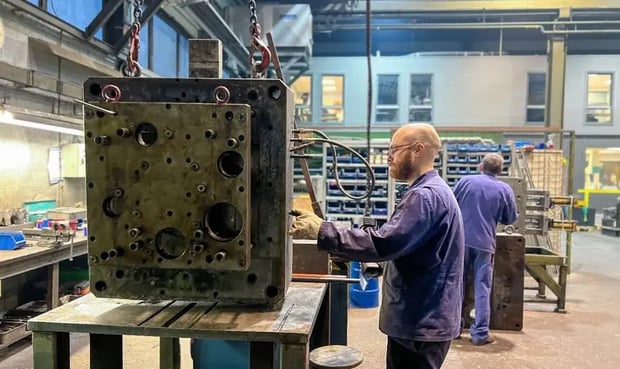Technician performing maintenance on large machinery in a workshop setting