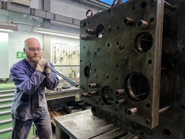 Technician using a tool to maintain a large piece of industrial machinery in a workshop