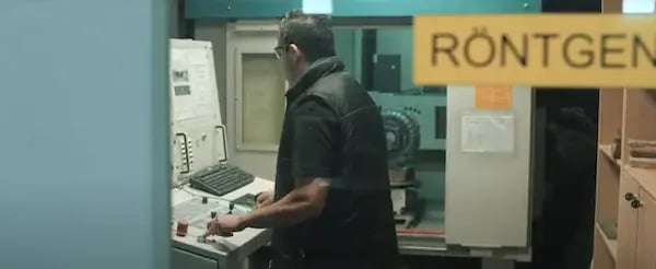 Quality assurance technician operating equipment in a room marked for X-ray testing