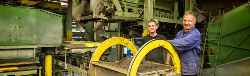 Medewerkers werken met zandgietmachines in een fabriek brede opname