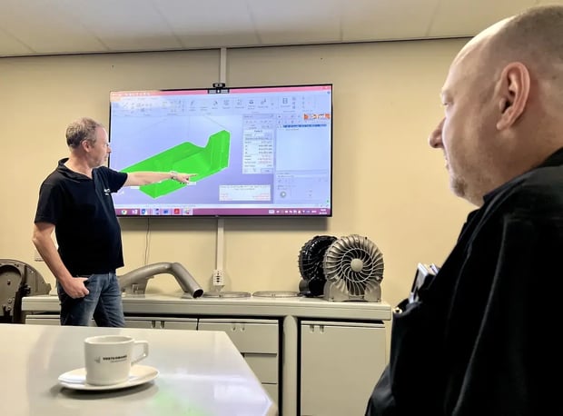 Employee giving a presentation on sand casting design using a screen in a meeting room