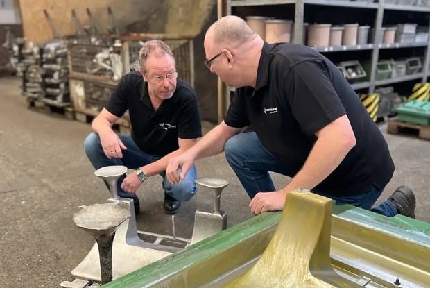 Werknemers inspecteren zandgietonderdelen op de fabrieksvloer