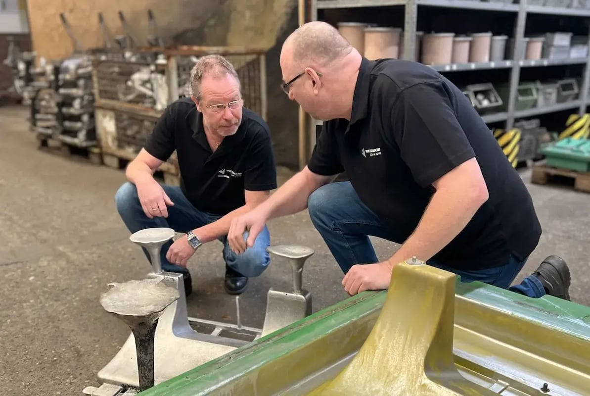 Werknemers inspecteren zandgietonderdelen op de fabrieksvloer