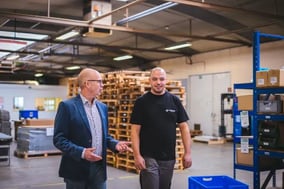Two employees walking and talking in factory warehouse area