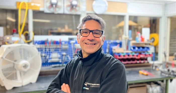 Empleado sonriendo a la cámara en el área de taller con herramientas de fondo