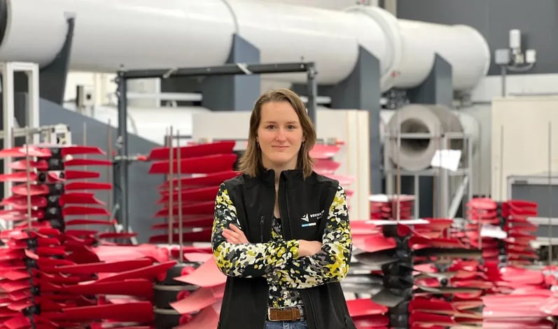 Werknemer staat met gekruiste armen voor onderzoeks- en ontwikkelingsfaciliteit met ventilatorbladen