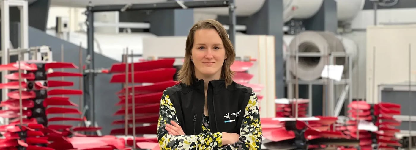 Employee standing with arms crossed in research and development facility with fan blades in background