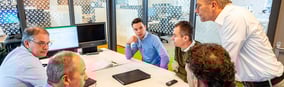 Réunion d'équipe autour d'une table avec six employés discutant affaires dans un bureau moderne