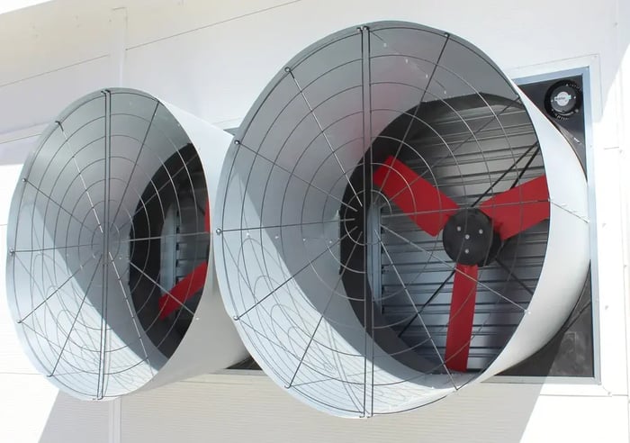 Dual industrial exhaust fans with red blades and protective grille